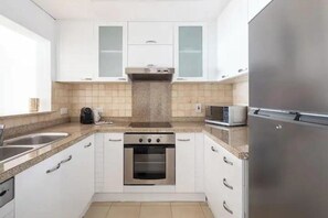 A compact kitchen with white cabinets, a built-in oven, a microwave, and a stainless steel refrigerator. - ELEGANT 1 Bed with Marina View - Marian Tower - Dubai Marina (Dubai)