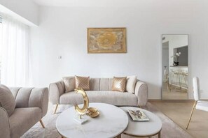 A modern living room with a sofa, two coffee tables, and a decorative piece on the wall. - ELEGANT 1 Bed with Marina View - Marian Tower - Dubai Marina (Dubai)