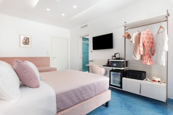 Una habitación de hotel moderna con una cama, un televisor, un armario y un escritorio con una computadora.