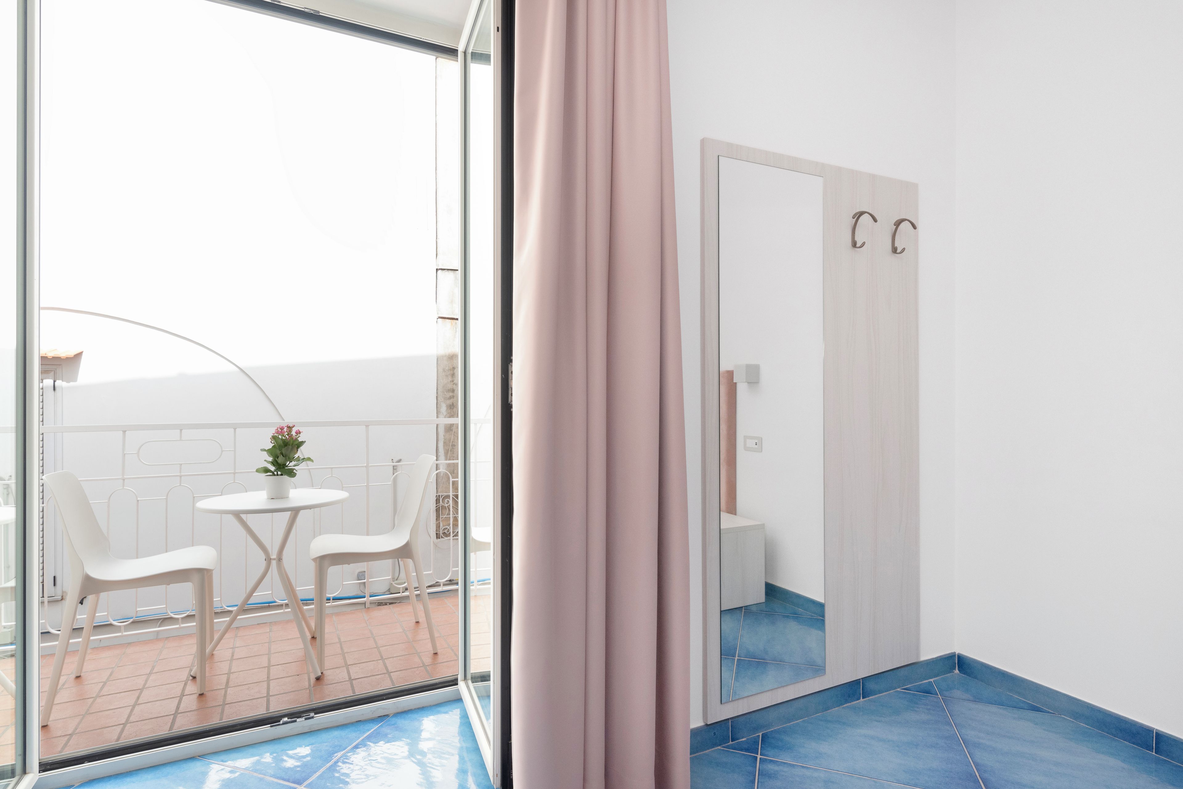 A modern bathroom with a large mirror, a shower area, and a small seating area with chairs and a table.