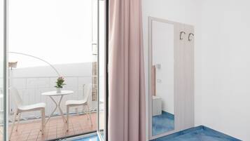 A modern bathroom with a large mirror, a shower area, and a small seating area with chairs and a table.