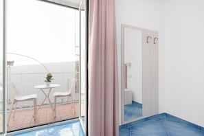Un baño moderno con un espejo grande, zona de ducha y un pequeño rincón de descanso con sillas y una mesa.