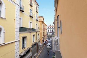 A narrow street with buildings on either side, a clear sky, and a few pedestrians. - Cornelia Rooms (Sorrento)