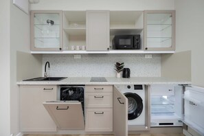 Une cuisine compacte équipée d’un lave-vaisselle, d’une machine à laver et d’un four à micro-ondes.
