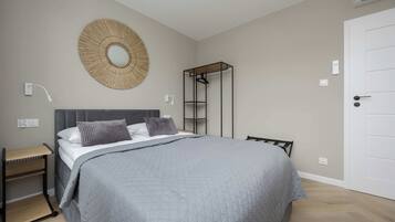 A bedroom with a bed, bedside tables, a wardrobe, and a wall-mounted mirror.