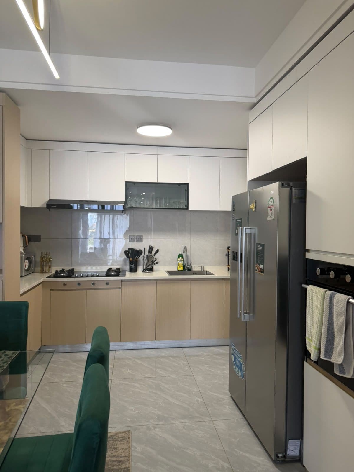 A modern kitchen with a built-in oven, a refrigerator, and a dining area with a green sofa.