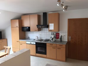 Eine kleine Küche mit Holzausstattung, einer Mikrowelle, einer Kaffeemaschine und einem Herd.