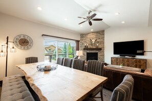 Un comedor amplio con una mesa y sillas de madera, un reloj de pared grande y un ventilador de techo.