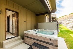 Ein Whirlpool mit Holzverkleidung, eine Tür, die zu einem Badezimmer führt, und eine Steinwand im Hintergrund.