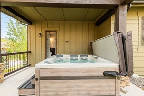 Un jacuzzi en un porche con una pared de piedra y una terraza de madera.