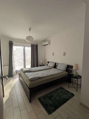 A bedroom with a bed, two bedside tables, a lamp, a radiator, and a window with curtains. - Astoria Panorama Duplex, Self-check-in, Automated, Large, 2lvl apt with a view (Budapest)