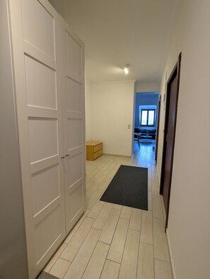 A hallway with a wooden floor, a black mat, and a set of white double doors. - Astoria Panorama Duplex, Self-check-in, Automated, Large, 2lvl apt with a view (Budapest)