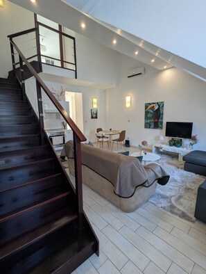 Un intérieur moderne comprenant un escalier, un canapé, un coin repas et un téléviseur.