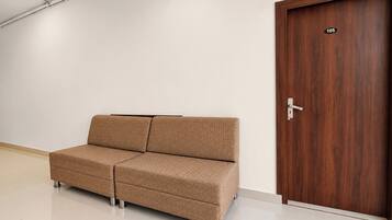 Una habitación con un sofá marrón, una puerta de madera con un número y una pared blanca.