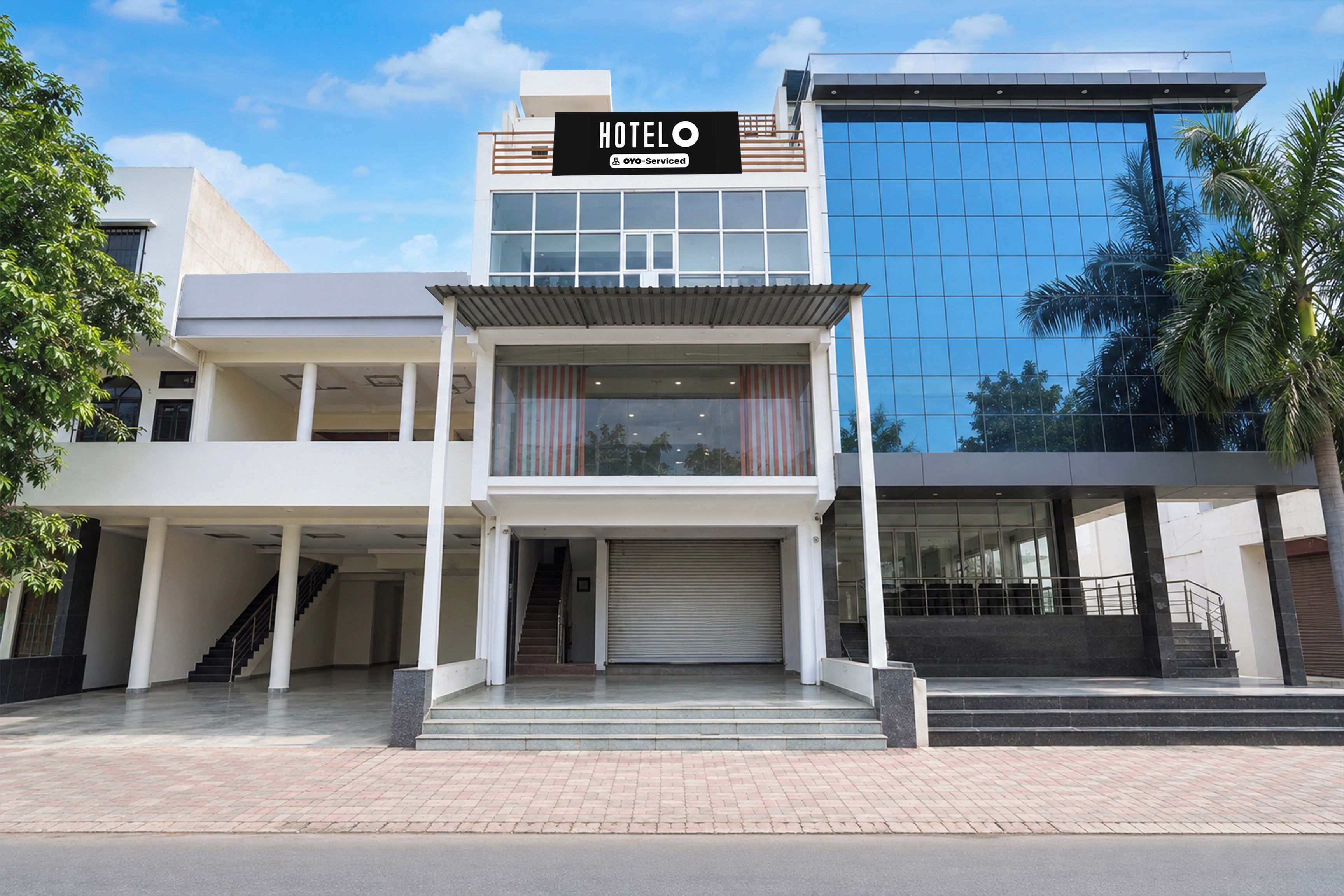 A hotel with a modern facade, a sign indicating it is serviced by OYO, and a staircase leading to the entrance.