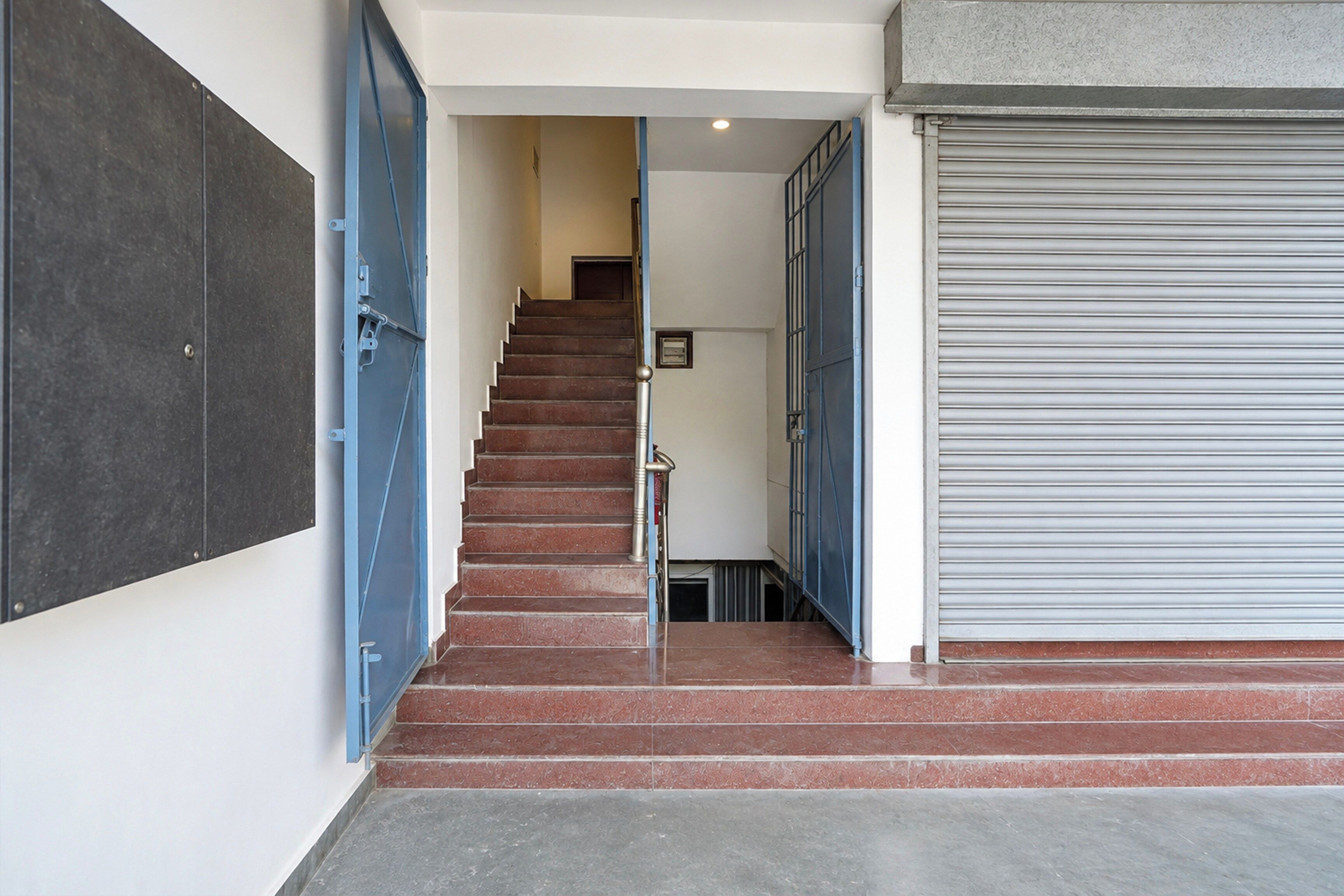 Una escalera conduce a un piso superior, con una puerta metálica cerrada a la derecha.