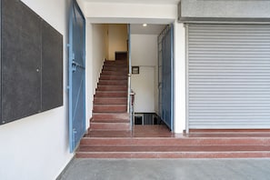 A staircase leading to an upper floor with a closed metal shutter door on the right. - Hotel O Munsi Puliya Metro Lucknow (Lucknow)