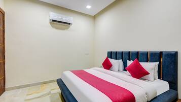 A hotel room with a bed, a headboard, an air conditioning unit, and a tiled floor.