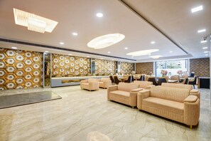 A spacious lobby with a reception desk, seating area, and decorative wall patterns. - Hotel Royal Harmony (Faridabad)