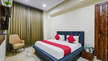 Una habitación de hotel con una cama, una silla, una puerta de madera y un ventilador de techo.