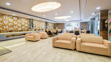 Un hall espacioso con mostrador de recepción, asientos cómodos y diseños decorativos en las paredes.