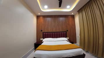 Un dormitorio con cama, ventilador de techo, iluminación empotrada, paneles de madera y cortina.