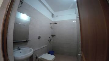 Een compacte badkamer met een wastafel, toilet en douche.
