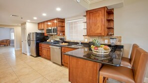 Una cocina moderna con armarios de madera, electrodomésticos de acero inoxidable y una isla central con un frutero.