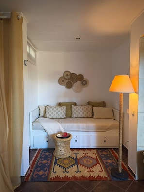 Ein Schlafzimmer mit Bett, Nachttisch, Lampe, Wanddekoration und einem gemusterten Teppich.