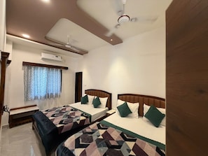 A bedroom with two beds, a ceiling fan, an air conditioning unit, and a window with curtains.