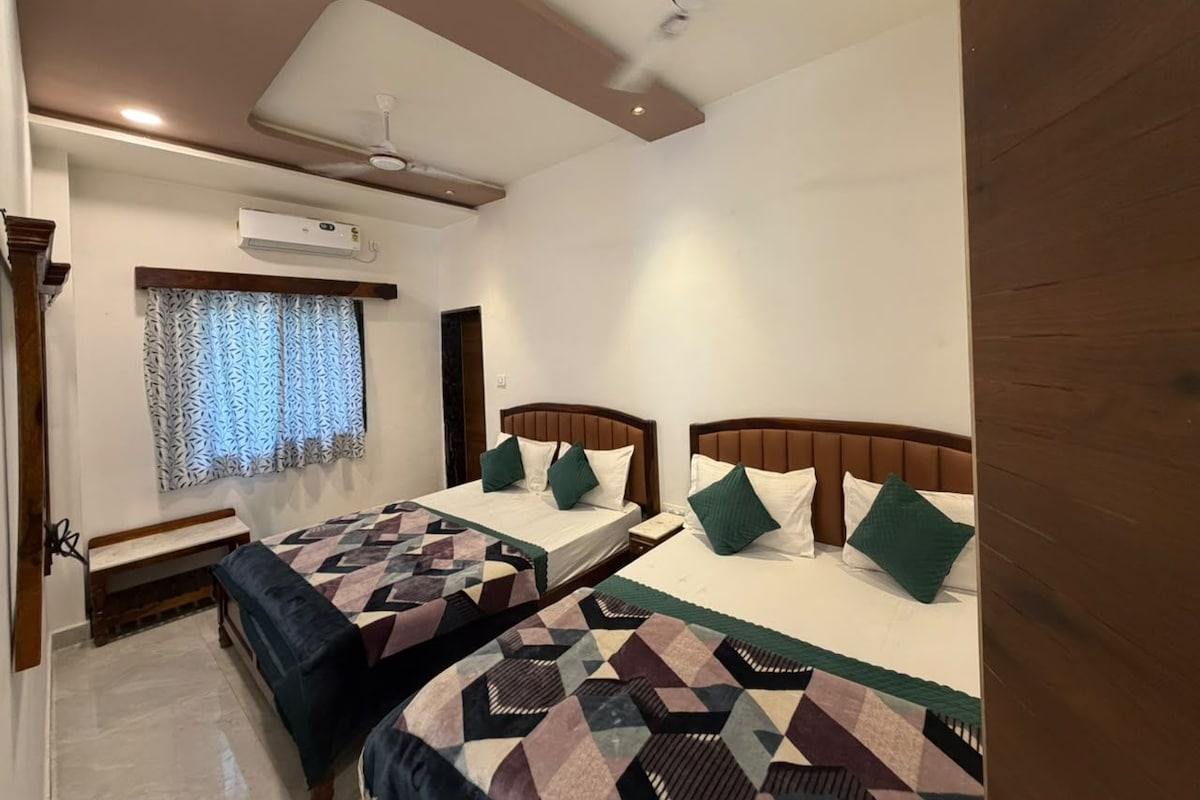Een hotelkamer met twee bedden, een bankje, een plafondventilator en een airconditioning.