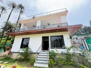 A two-story building with a balcony, a staircase leading to the entrance, and a sign indicating it's part of Hariniwas Resort.