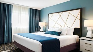 A hotel room with a large bed, two bedside tables, and a view of the outdoors through a window with curtains. - WorldMark Anaheim - 1BR Suite, Rooftop Hot Tub Near Disneyland (Anaheim)