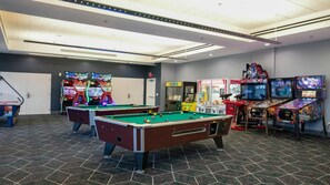 A pool table with a billiards cue, a pool table, and a video game arcade with various games. - WorldMark Anaheim - 1BR Suite, Rooftop Hot Tub Near Disneyland (Anaheim)