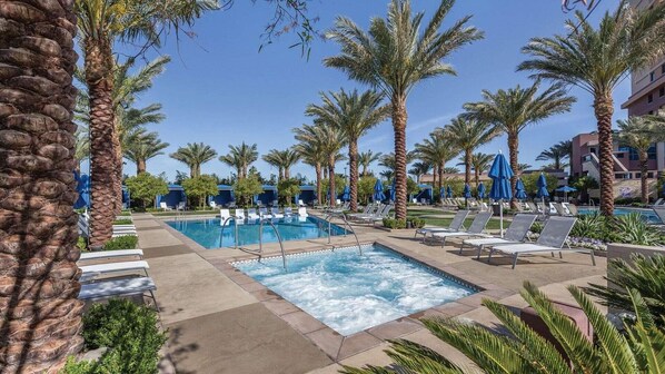 Un espace piscine avec des chaises longues et des palmiers.