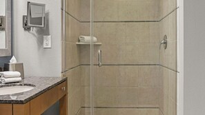 Een badkamer met een douche, een wastafel en een spiegel.