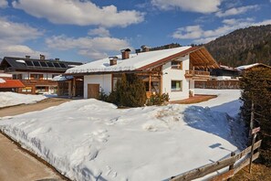 Ein verschneiter Wohnbereich mit Häusern, die Holzbalkone und Solaranlagen haben.