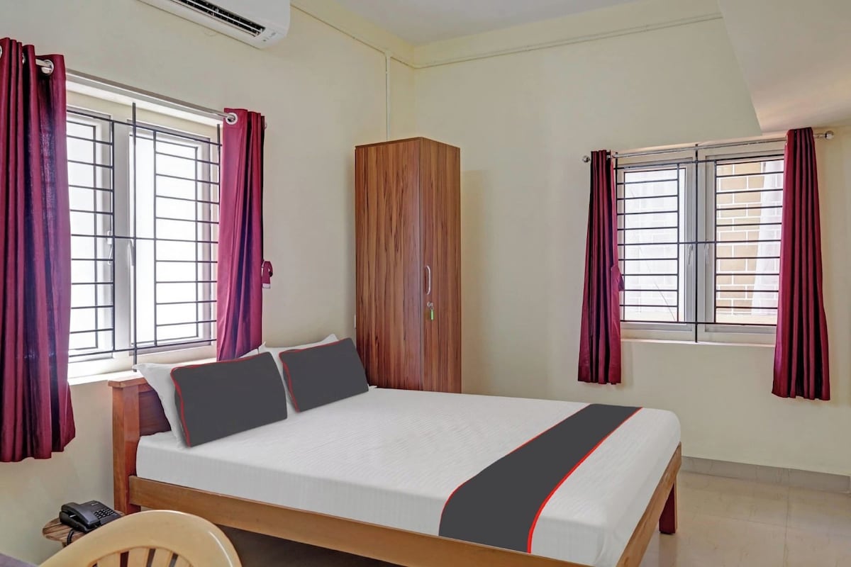 Une chambre à coucher avec un lit, une armoire et deux fenêtres avec des rideaux.