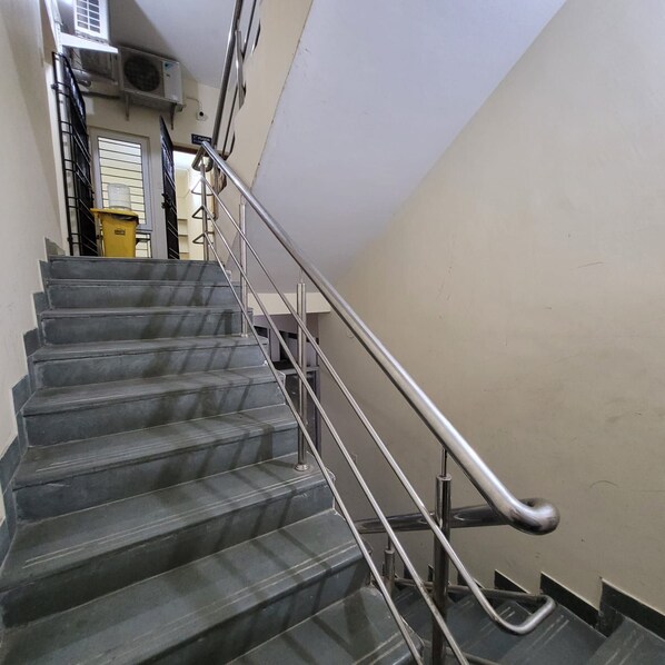 Un escalier avec des rampes en métal et un extincteur jaune fixé au mur.