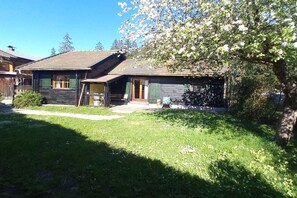 Ein traditionelles Holzhaus mit einem geneigten Dach, einer Veranda und einem kleinen Garten.