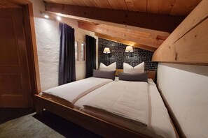 Ein Schlafzimmer mit zwei Betten, einer Holzbalkendecke und einer Wand mit Muster.