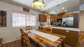 A kitchen with wooden cabinets, a stainless steel refrigerator, and a dining area with a wooden table and chairs.