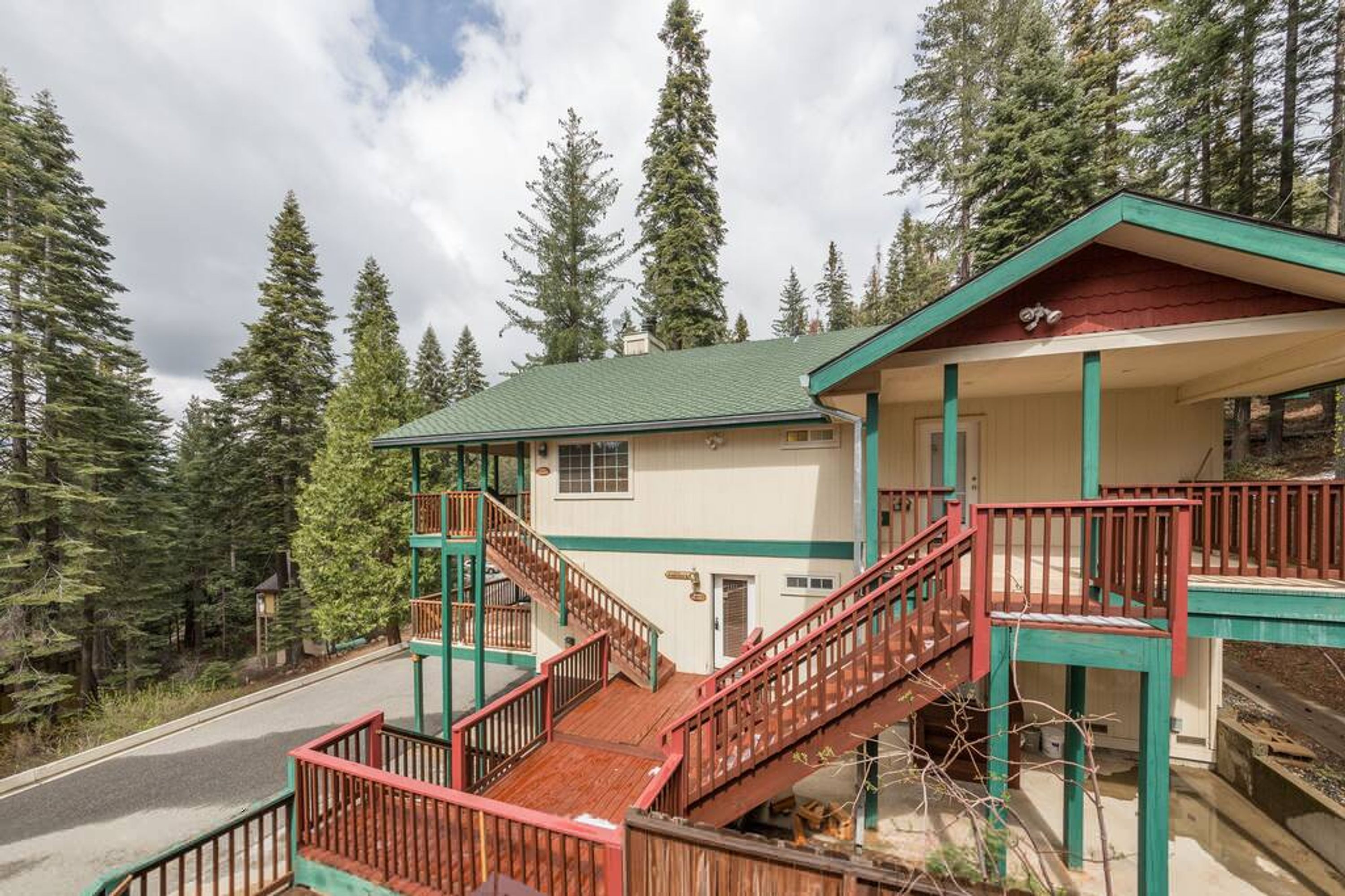 A two-story lodge with a green roof, wooden stairs, and a balcony.