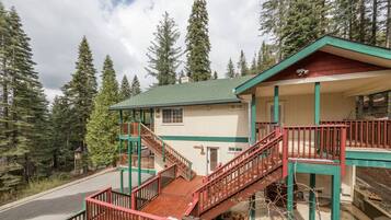 A two-story lodge with a green roof, wooden stairs, and a balcony.