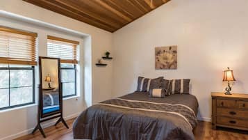 Un dormitorio con cama, mesitas de noche, un espejo y una ventana con persianas.