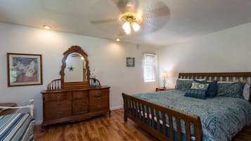 A bedroom with a wooden bed, a dresser, a mirror, and a ceiling fan.
