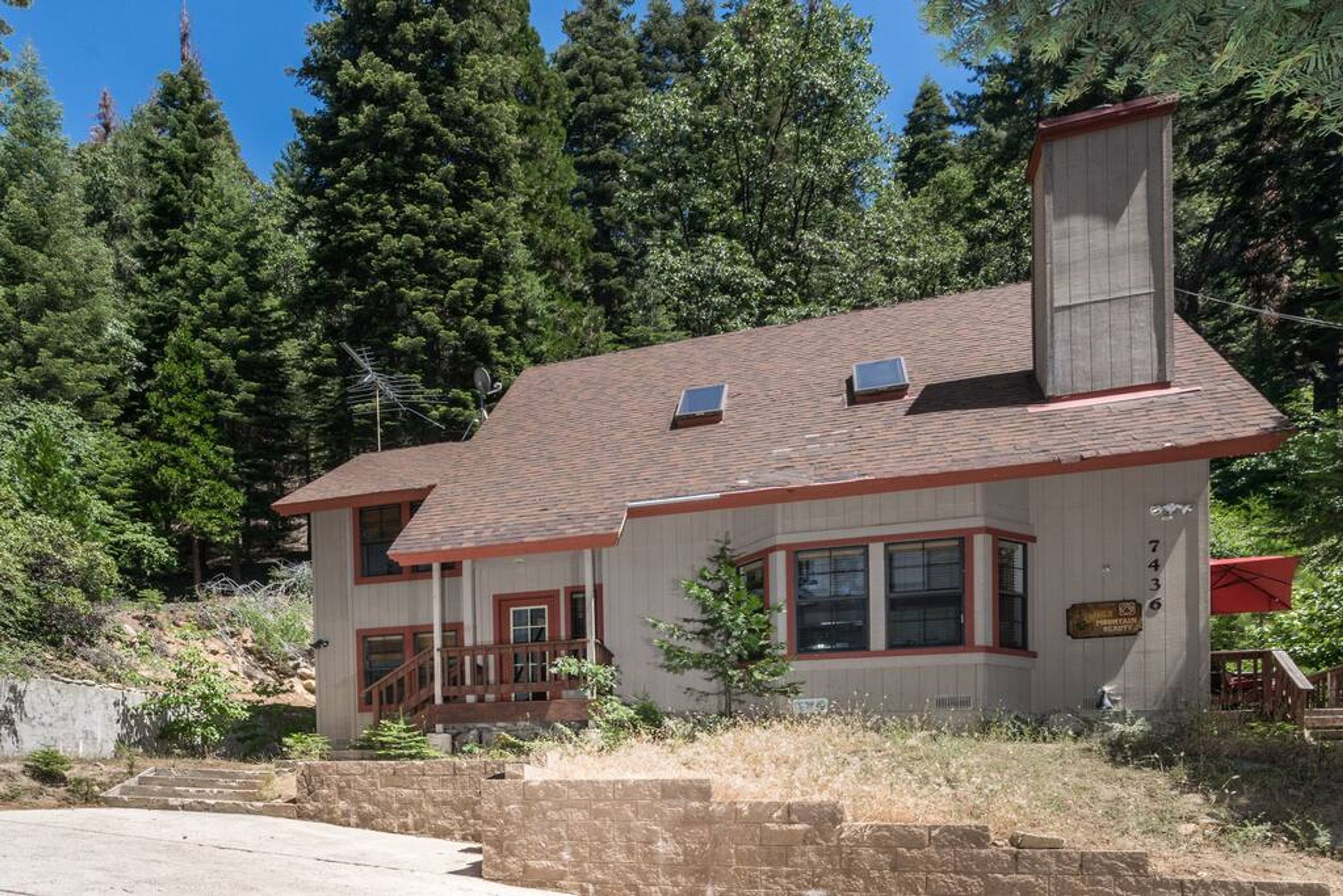 A two-story house with a chimney, a front porch, and a small deck.