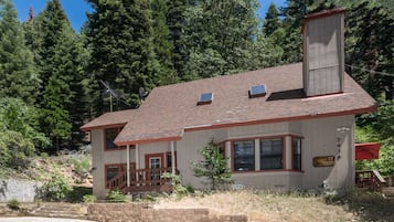 A two-story house with a chimney, a front porch, and a small deck.