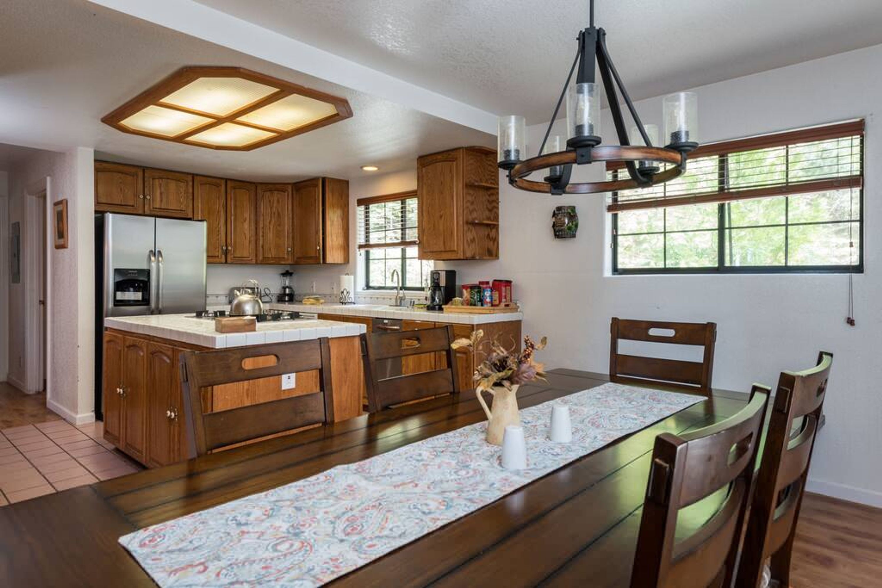 Una cocina amplia con armarios de madera, una isla central y un comedor con una mesa dispuesta para cuatro.