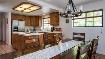 Una cocina amplia con armarios de madera, una isla central y un comedor con una mesa dispuesta para cuatro.